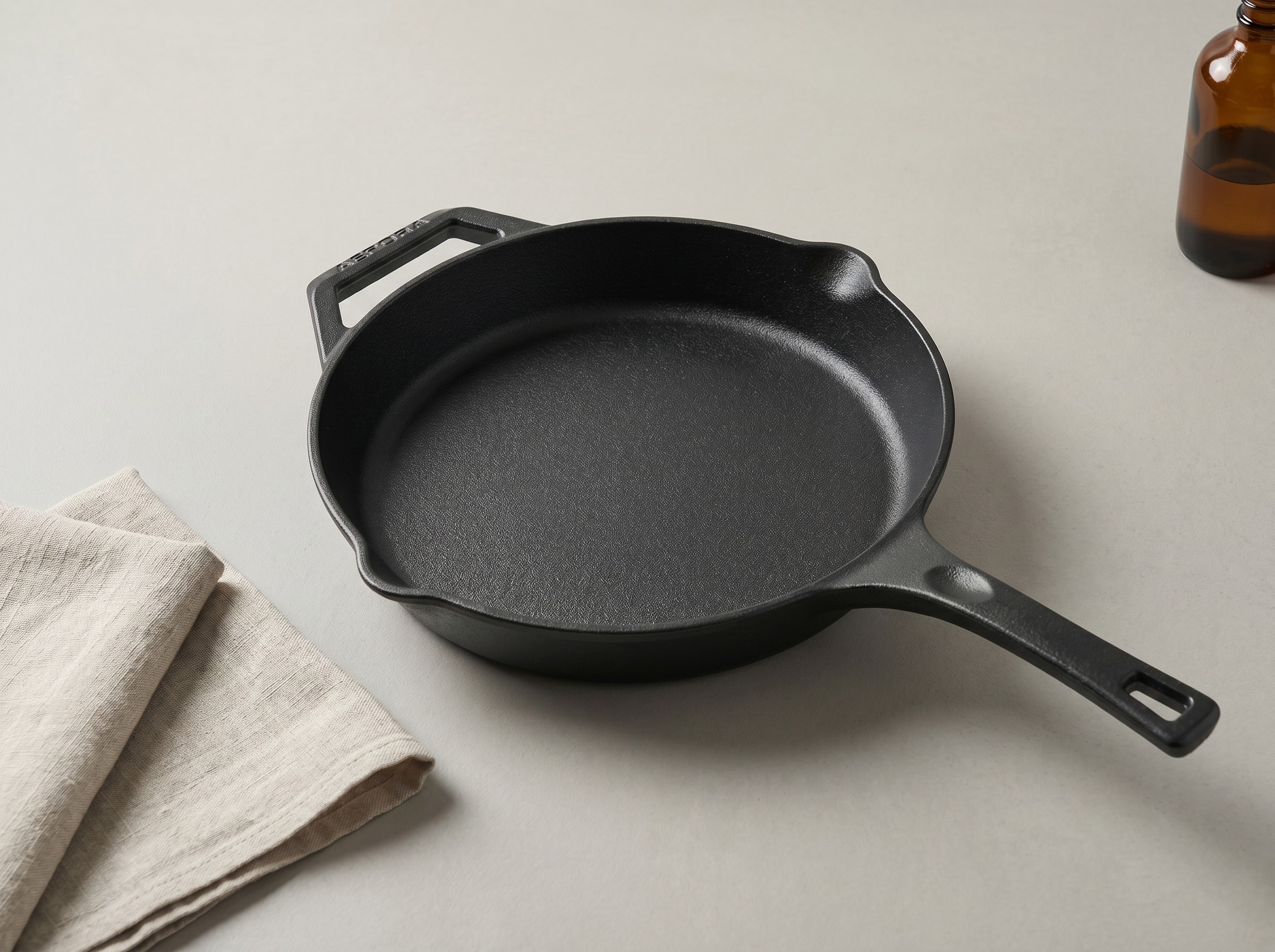 AEPORA cast iron skillet resting on a neutral surface with a linen cloth alongside, clean and ready to use